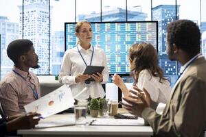 Diverse group of professionals meeting to discuss a new development strategy, utilizing infographics and monthly analysis numbers to reach target and accomplish organizational goals. photo