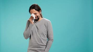 Portrait of troubled man weeping feeling saddened and rattled by events, isolated over studio backdrop. Person crying, wiping tears with handkerchief, left speechless by troubling news, camera B photo