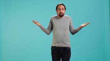 Man shrugging shoulders, unable to provide answer, having detached apathy facial expression. Apathetic person doing hand gesturing showing lack of knowledge, studio background, camera A photo