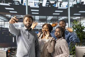 African american coworkers take photos on mobile phone at the office on a break, having fun in a business corporation workplace. Employees solving operations and tasks, making memories.