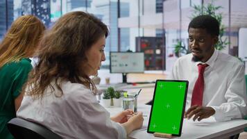 Job applicant and employer discussing in an interview with isolated mockup display on a device, high end corporate office. Businessman and HR recruiter share career development ideas. Camera B. photo