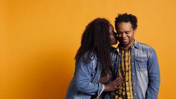 Funny wife making her husband laugh about sweet nothings, whispering things into his ear and amusing each other. Cute romantic married couple having secrets in studio. Camera B. photo