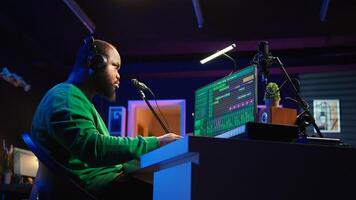 African american music producer twisting knobs on mixing console, produce tracks with sound effects. Artist composing songs in post production, operates on digital software in home studio. Camera B. photo