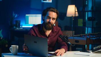 Influencer in studio endorsing laptop from brand sponsoring , talking in microphone. Content creator does influencer marketing by promoting notebook, recording with high tech mic, camera A photo