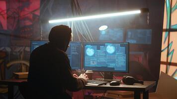 Hacker using high tech computer system to run malicious code in foggy dark basement. Rogue programmer committing illegal activities using PC in neon illuminated criminal hideout, camera B photo