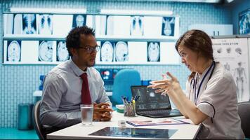 General practitioner consults patient about diagnostic test results, utilizing medical technology for accurate analysis and care management in a clinical environment. Healthcare provider. Camera B. photo
