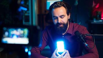 Tech guru filming technology review of mini led lights, offering feedback, close up shot. Friendly online star showing filming equipment to subscribers, talking in mic, camera A photo