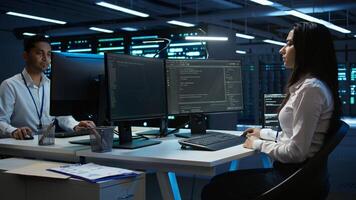 Team of technicians in data center designing, implementing and managing infrastructure to ensure optimal performance and reliability. Teamworking colleagues in server room coding on computer, camera B photo