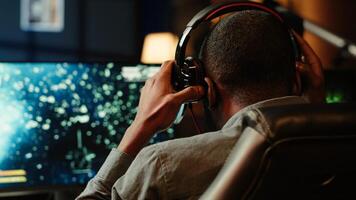 Man playing SF space videogame on PC screen, shooting asteroids, putting headphones on. Close up of gamer enjoying spaceship flying game on computer desktop display, navigating through meteorites photo