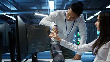 Team of admins in data center ensuring system can handle networking tasks. Teamworking colleagues in server room tracking network traffic with PC, making improvements, camera B photo