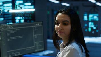 Portrait of cheerful engineer in data center installing software on computer, troubleshooting issues. Smiling IT specialist in server room establishing performance benchmarks photo