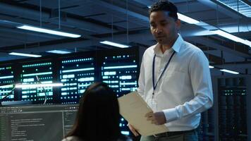 Management executive in data center ensuring system can handle networking tasks. Coworkers doing brainstorming in server room, tracking network traffic with PC, making improvements, camera A photo