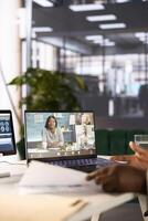 Close up of CEO in startup office holding videoconference meeting with remote workers, discussing project plan. Supervisor at computer desk in internet videocall with employees working from home photo