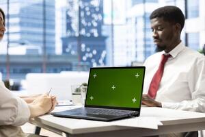 HR professional using green screen laptop during interview to ensure job candidate possesses necessary qualifications. Recruiter presenting salary package to applicant on chroma key notebook photo