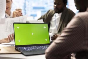 Organizational staff looking at device with green screen during a meeting, ensuring progress for an expansion project. Professional forecast affiliates sharing ideas for data management. photo