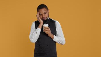 Tired overworked waiter drinking a coffee cup to relax after long shift, working in catering and service oriented environment. Employee feels fatigued and serving caffeine drink. Camera B. photo