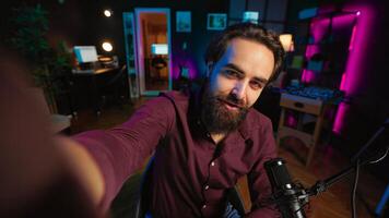 Joyous influencer using professional recording equipment to film vlog channel intro, talking with subscribers. POV shot of upbeat vlogger recording himself greeting fans, covering different subjects photo