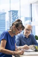 Senior woman reading contract terms and signing in a meeting with financial advisor, exploring retirement plan options. Middle aged client agreeing to pension planning for the future. photo