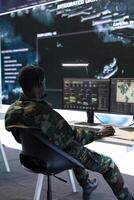 Army specialist working with advanced computer systems and cctv data for surveillance missions, gather intelligence to protect national interests. Strategic planning in a high tech control room. photo