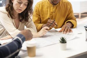 Realtors meeting with business owner to go over all contract terms before leasing the real estate high class office space. Analyzing and reviewing layout on architectural blueprints plans. photo