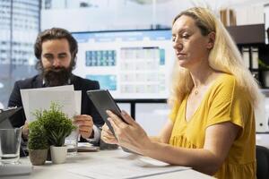 Financial adviser presents market analytics to clients using large display and tablet device, teaching how to build portfolio. Broker showing stock exchange charts to parent and girl photo