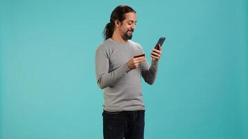 Man adding payment method on website, isolated over blue studio background. Cheerful person excited to do online shopping, carefully typing credit card information, camera A photo