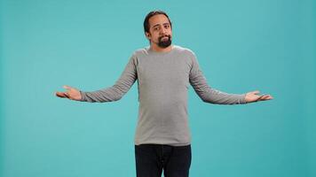 Man shrugging shoulders, expressing uncertainty or helplessness, having troubled facial expression. Person unable to provide assistance to friend, feeling powerless, studio background, camera A photo