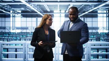 African american admin greeting inspector arriving in data center to supervise operations. IT expert in server hub workspace doing hand shake with supervisor monitoring performance, camera B photo