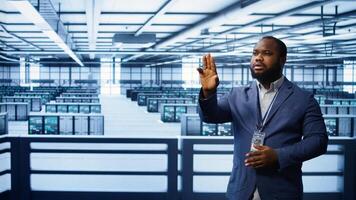 System administrator looking at holograms in data center, monitoring equipment. Employee in server farm interacting with futuristic augmented reality AI visualization, camera B photo