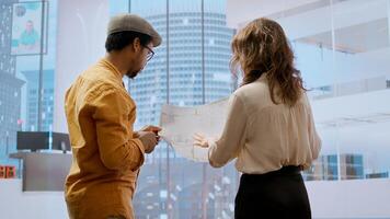 Business professional and real estate broker reviewing blueprints on laptop for high class office leasing contract, discussing the architectural design and layout. Planning to buy property. Camera A. photo