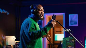 Young artist singing his new song creation on microphone gear, editing his recordings to adjust volume levels with mix and master techniques. Singer composing a melody, stereo tools. Camera A. photo