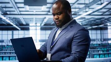 Software developer in data center runs diagnostic tests and error checking utilities on laptop to fix problems. IT expert looking for network issues affecting rigs performance using notebook, camera B photo