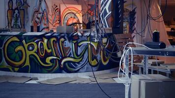Desolate headquarters used by gang members with graffiti drawings sprayed on walls. Rubble in ghetto hideout after criminals rushed to evacuate place, dolly in camera shot photo