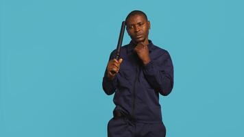 Portrait of security guard scratching head with baton while overseeing premises, thinking. Pensive private law enforcement worker daydreaming, rubbing chin, studio backdrop, camera B photo