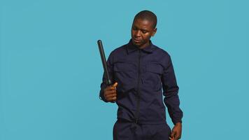 Security guard removing baton from belt, preparing to attack suspects. Portrait of bodyguard pointing finger towards truncheon, threatening to subdue criminals, studio background, camera B photo