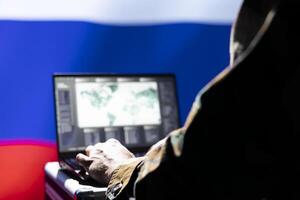 Russian soviet army expert analyzes aerial reconnaissance data to come up with tactics gaining battlefield advantage. Kremlin regime agent in command room controls drones attacking strategic targets photo