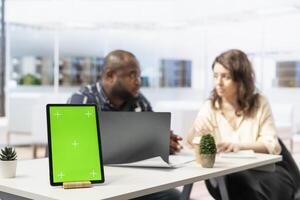 Real estate agent presenting office space layout next to chroma key display, reviewing blueprints with client during an office tour. Businessman negotiating leasing contract terms. photo