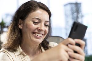 Director CEO taking a break from work and answering text messages on her smartphone, discussing with partners or friends in her high end business office. Social media updates online. photo