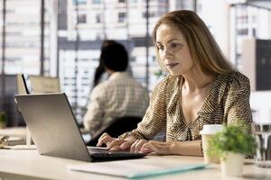 Female executive reviewing business operations at her desk, focused on project management. Employee analyzes performance metrics and budget allocations to optimize the enterprise strategy. photo