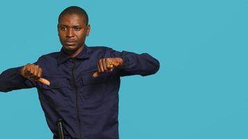 Security guard doing thumbs down sign gesturing, denying public access in restricted area. Portrait of bodyguard doing negative hand gesture, being dismissive, studio background, camera A photo