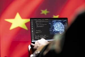 AI software on laptop used by Chinese security service programmer to commit terrorism attacks. Artificial intelligence tech used by CCP government to hack neighbor countries, isolated over China flag photo