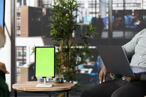 Isolated screen tablet next to manager working on laptop in office, coordinating company administrative operation. Supervisor reviewing business procedures on chroma key device photo