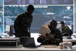 Army specialist in a control center manages satellite real time data, overseeing live surveillance footage for reconnaissance activity. Intelligence operations to support national defense mission. photo