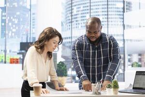 Realtor helping client to choose an office space in high class modern building, entrepreneur planning a relocation. People studying the architectural blueprints to present the property potential. photo