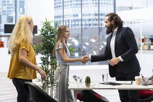 Welcoming financial advisor meeting with clients to recommend financial products and investments, greeting them. Investment strategies expert in workspace doing handshake with customers photo