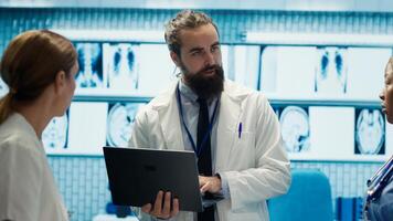 Neuroscience expert reviewing mri brain scan results with doctors, discussing the right treatment plan for disease prevention. Licensed neurologist and his staff examine tomography. Camera A. photo