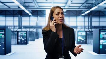 Technician in data center talking in phone call, doing yearly inspection. On field system administrator talking with manager in server hub during telephone call, monitoring servers, camera B photo