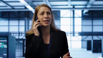 Technician in data center talking in phone call, doing yearly inspection. On field system administrator talking with manager in server hub during telephone call, monitoring servers, camera A photo