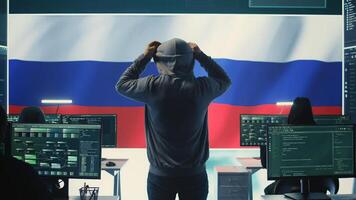 Russian hacker with a hood installing panic by misconception and manipulation, working in governmental cyber operations room. Impact of fake news and ideology propaganda in a hybrid war. Camera B. photo