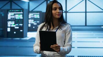 Admin in data center monitoring security threats with tablet, implementing cybersecurity measures. Specialist using device, ensuring compliance with regulations to protect data center gear, camera A photo